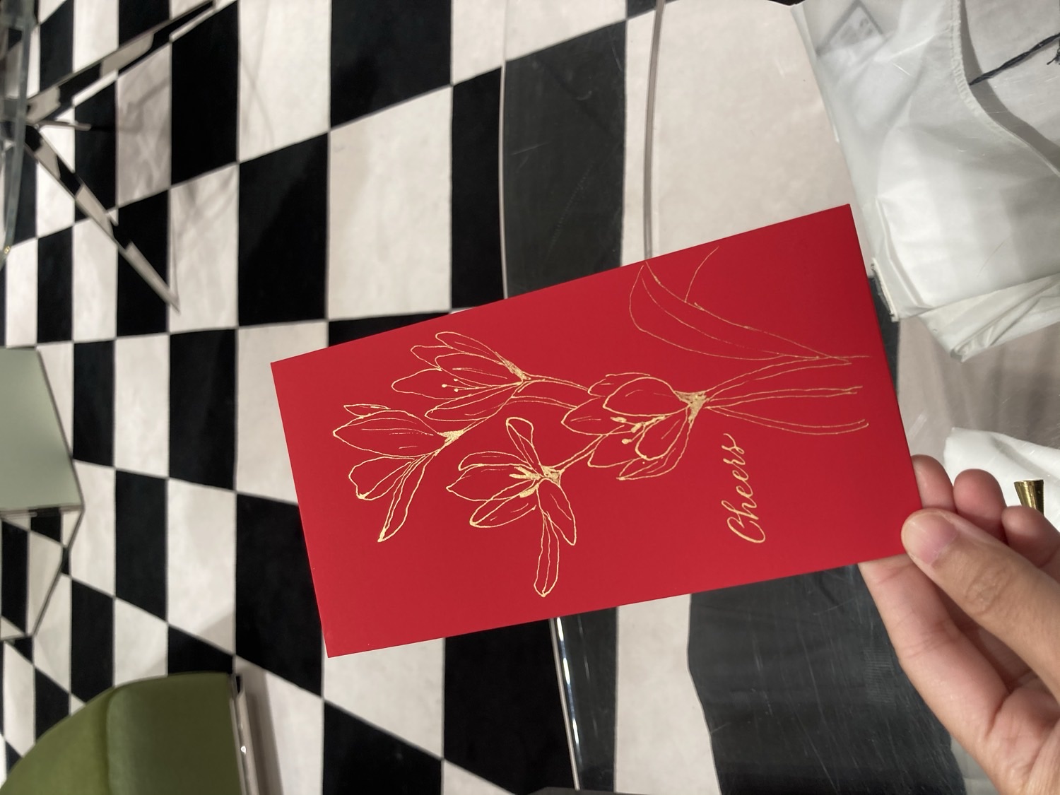 紅色利是封上以金色手繪木蘭花與 Cheers 花體字