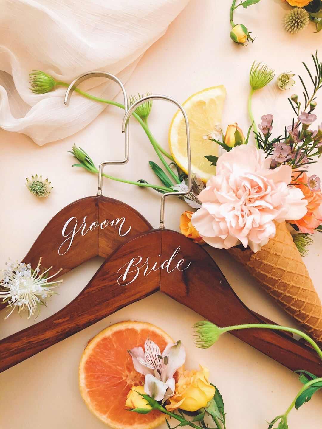 木質六角牌與長牌上以白色花體字寫著 Table 與 Cheers，周圍散落鮮花